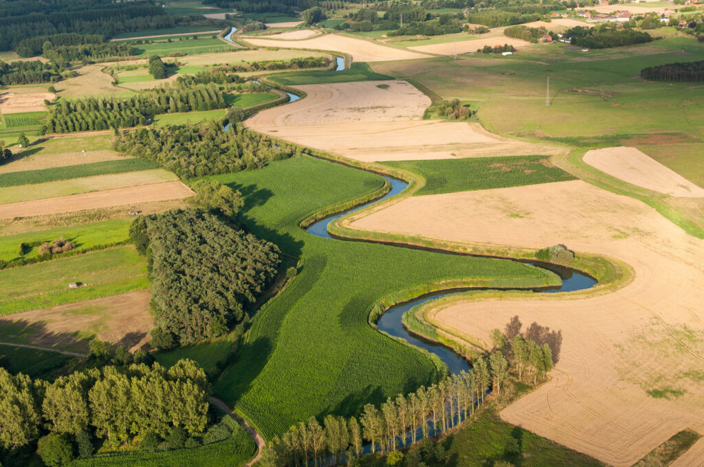 Les packrafters pagaient tranquillement sur le Demer, entouré d'une nature luxuriante et de champs verdoyants.