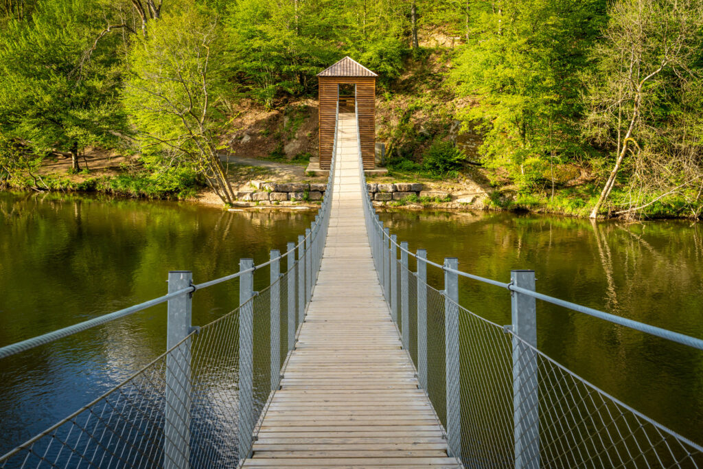 Packrafter auf der Semois: Ein Packrafter paddelt auf der friedlichen Semois, umgeben von dichten Wäldern und Hügeln des Semois Valley National Park.
