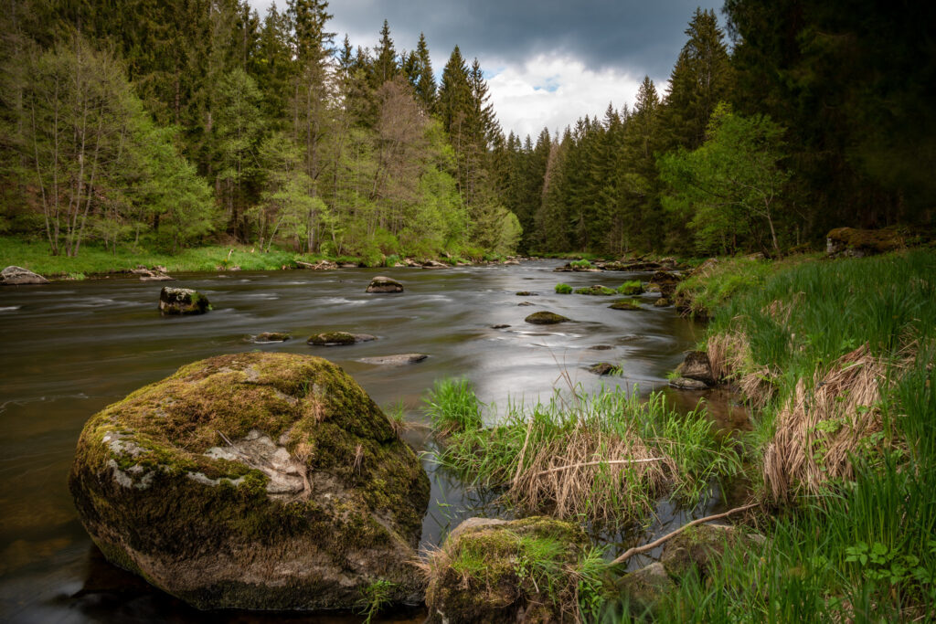 Deux randonneurs marchent le long de la rive du Blaibacher See, le soleil se couchant bas et se reflétant sur la surface de l'eau. Pluie sur la rivière