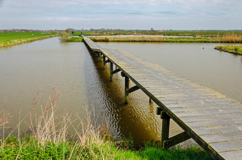Les pagayeurs partent avec leur packraft depuis l'embarcadère pour canoës du Fort Honswijk, avec le paysage verdoyant de Schalkwijk en arrière-plan.