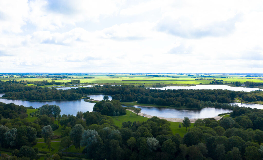 Eine Familie in einem Packraft paddelt durch die Schilfgebiete von De Alde Feanen in Friesland, umgeben von Natur und Vögeln.