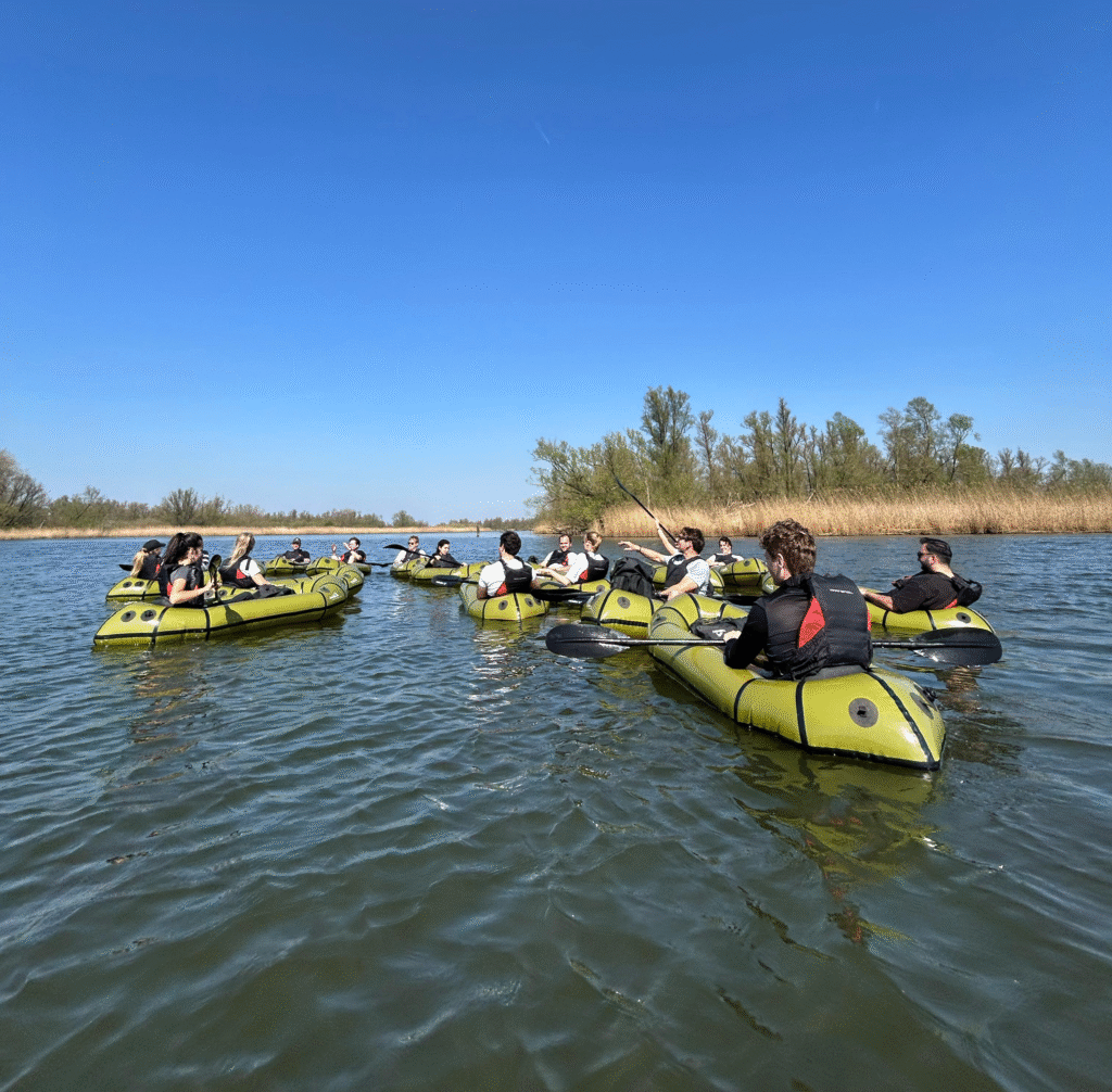Bedrijfsteam start wandeltrail met opgevouwen packrafts in rugzakken