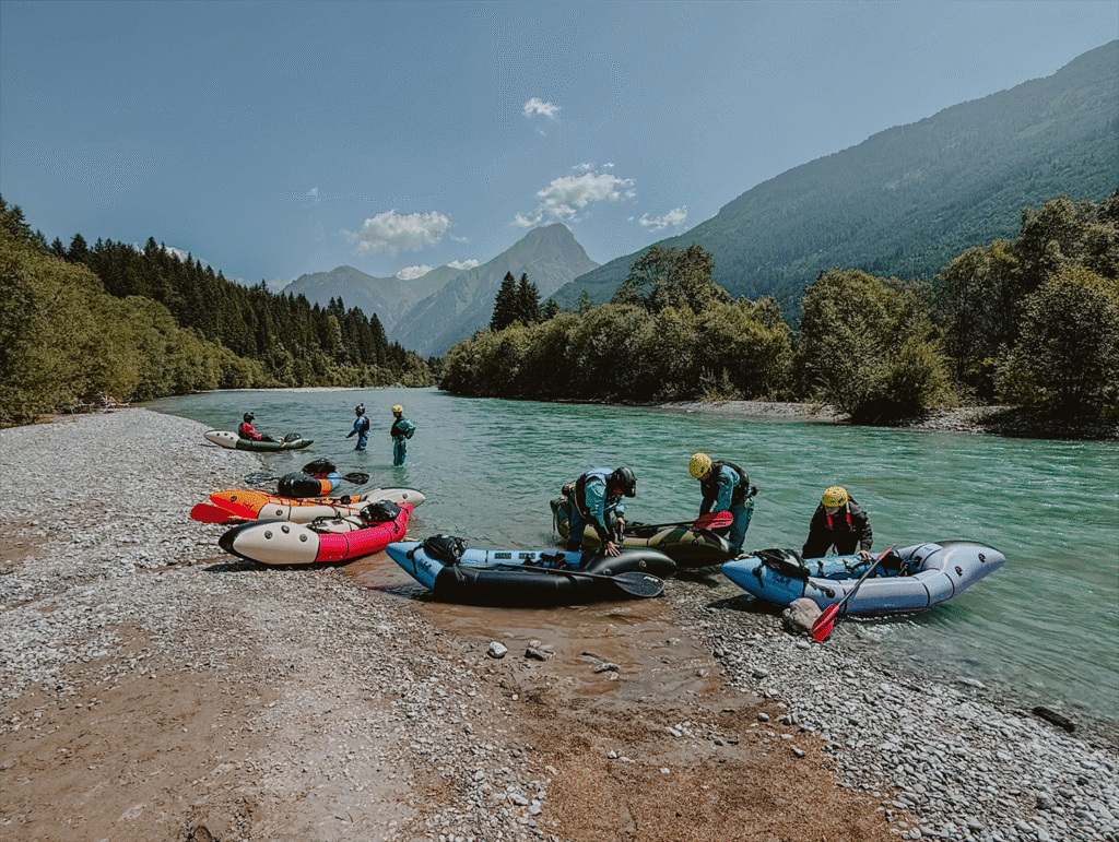 Packrafts aan de oever van een rivier met avonturiers in uitrusting