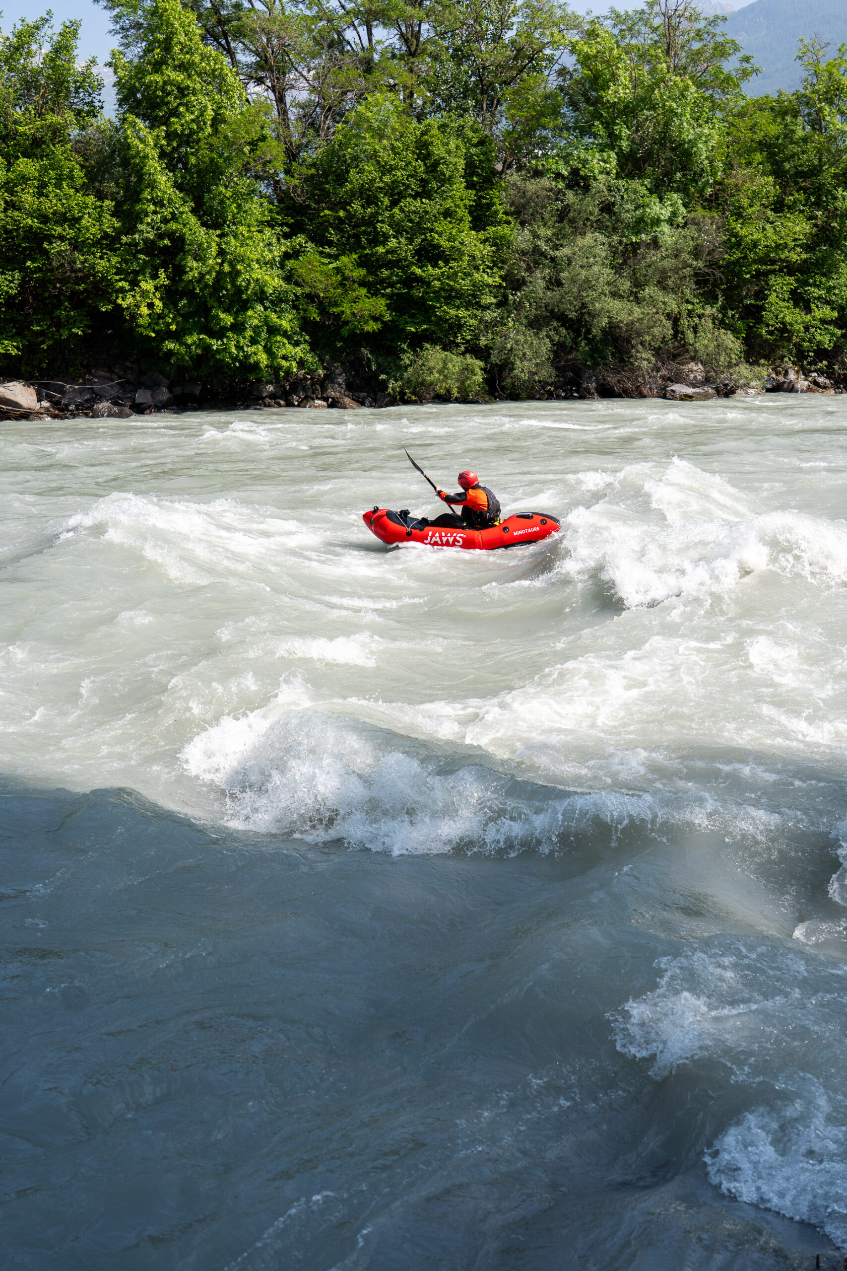 Avonturier met JAWS packraft op rivier omgeven door weelderige natuur