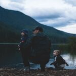 Vader met kinderen bij een meer, klaar voor een packraft avontuur in de natuur